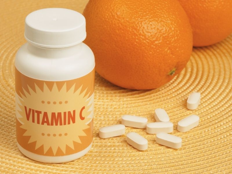 Vitamin c pill bottle next to an orange